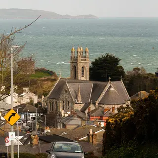 A church above the rooftops of a coastal village in east Cork