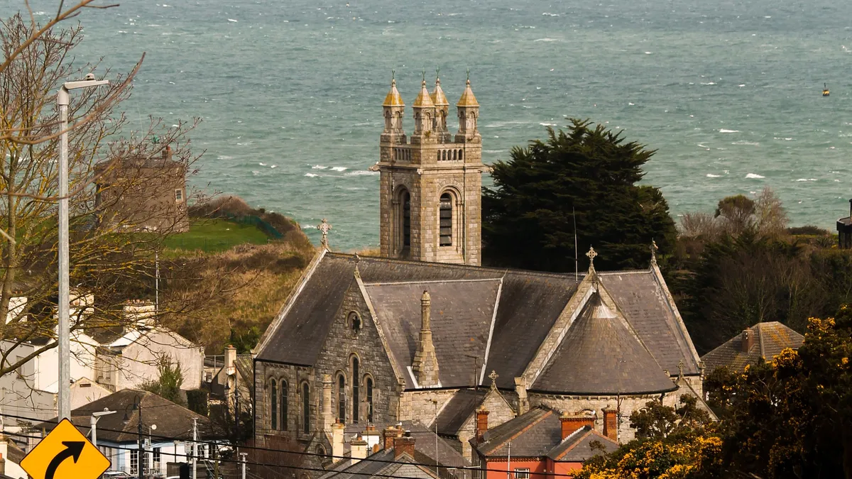 A church above the rooftops of a coastal village in east Cork