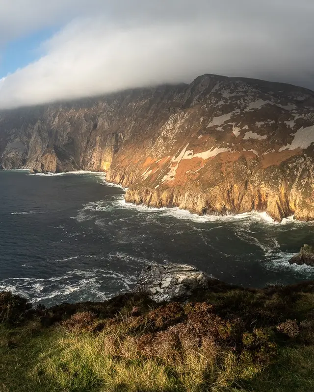Sunlight on the sea cliffs at Sliabh Liag with the Atlantic dark below them