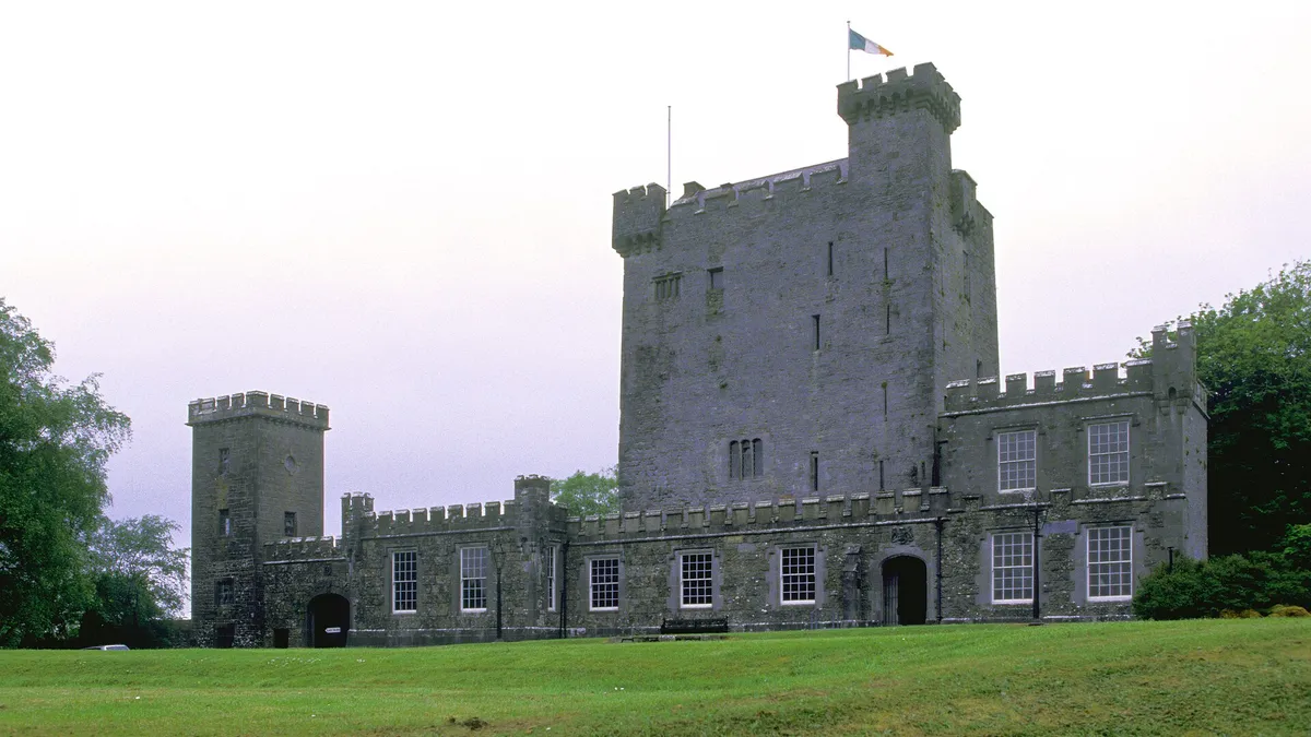 The tower house and castellated outer wall at Knappogue Castle above its lawn