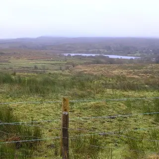 Rough grazing and fence posts running down to Garvagh Lough with hills beyond
