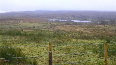 Rough grazing and fence posts running down to Garvagh Lough with hills beyond