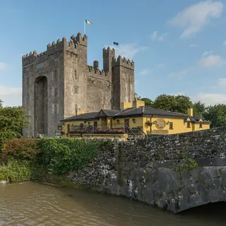 Bunratty Castle standing over the river, with Durty Nelly's pub in front of it