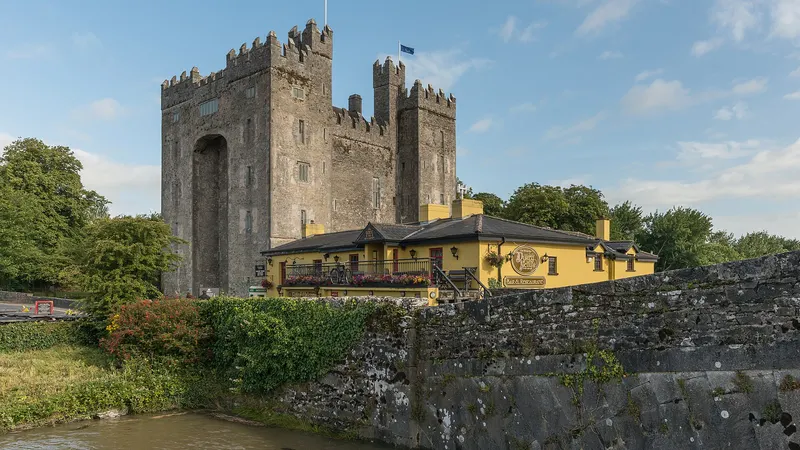 Bunratty Castle standing over the river, with Durty Nelly's pub in front of it