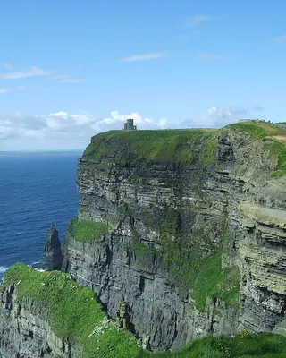 The Cliffs of Moher dropping to the Atlantic, with the clifftop path along the green edge