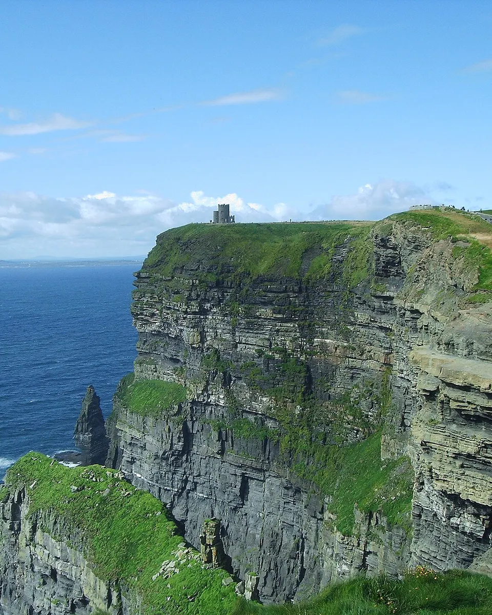The Cliffs of Moher dropping to the Atlantic, with the clifftop path along the green edge