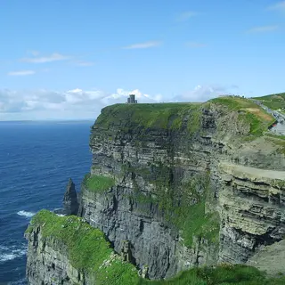 The Cliffs of Moher dropping to the Atlantic, with the clifftop path along the green edge