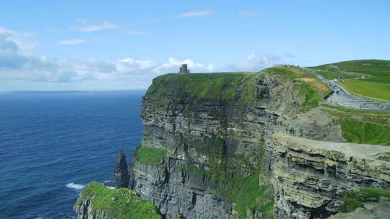 The Cliffs of Moher dropping to the Atlantic, with the clifftop path along the green edge