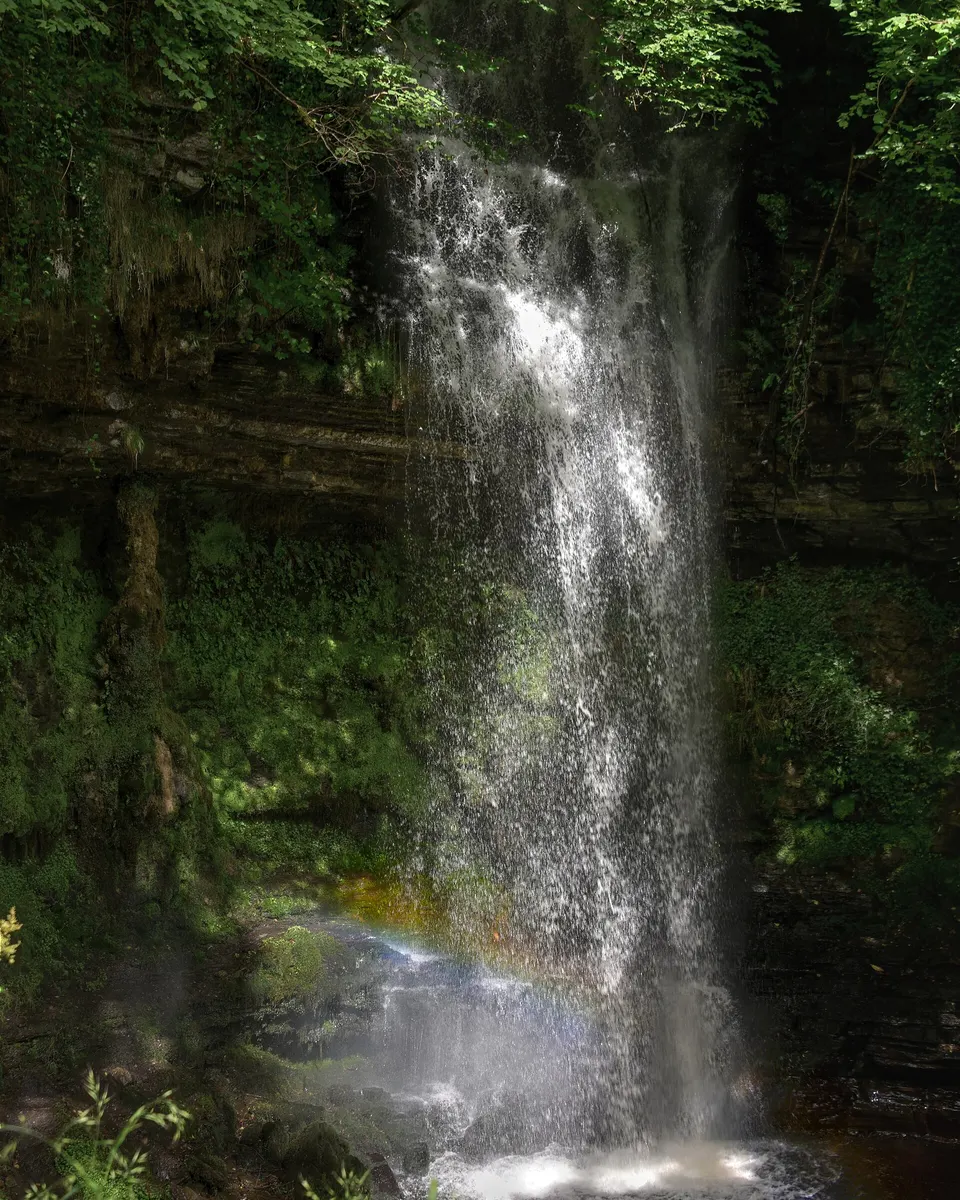Water falling in a sheet down the rock face at Glencar into the pool below