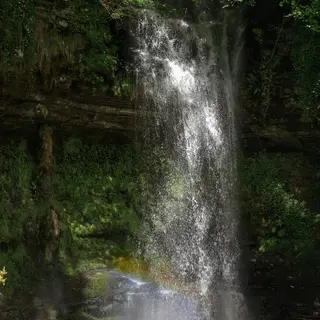 Water falling in a sheet down the rock face at Glencar into the pool below