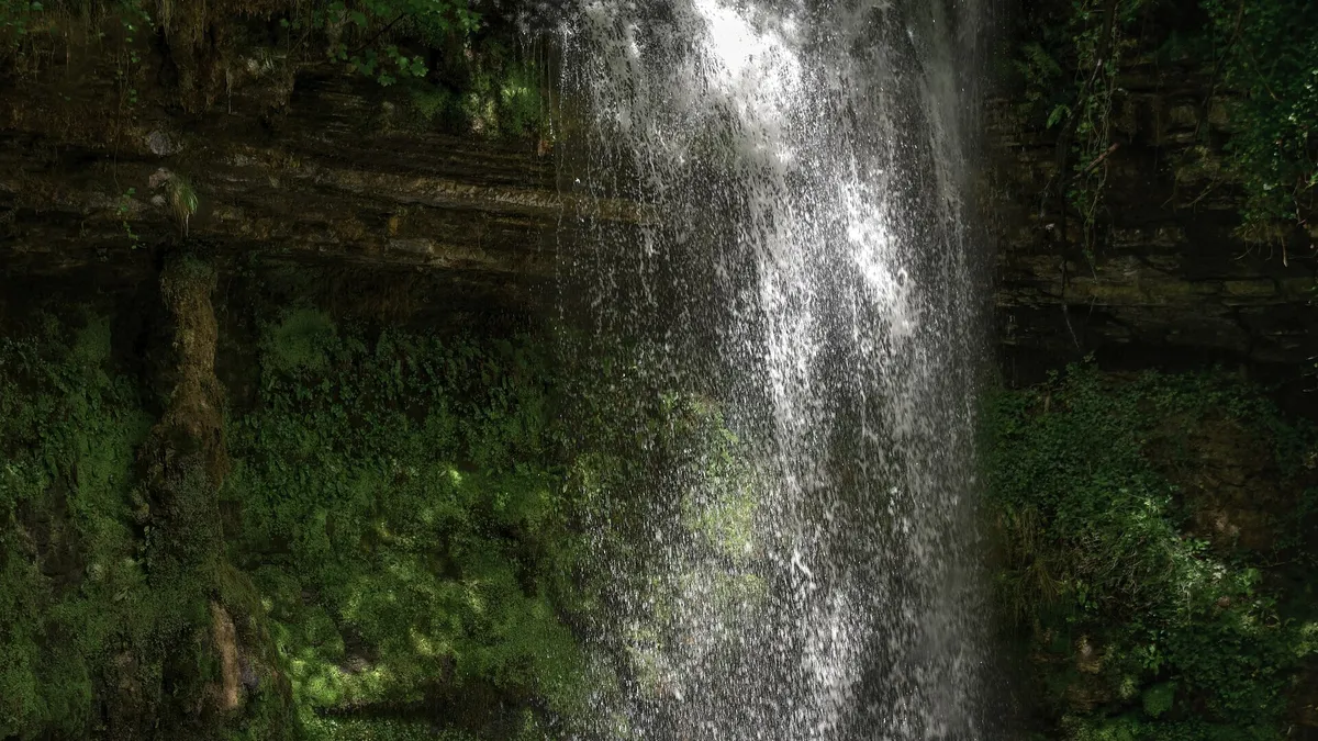 Water falling in a sheet down the rock face at Glencar into the pool below