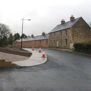 New stone paving and kerbs along the street of houses at Mullan Village