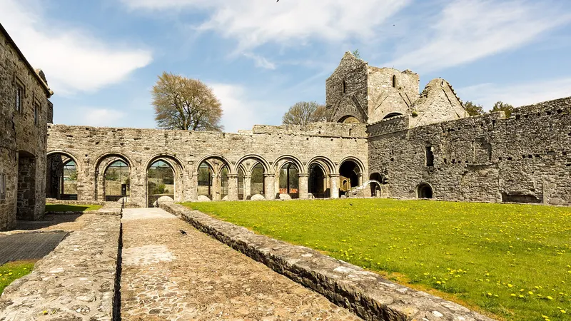 The cloister of Boyle Abbey with its round arches and the tower behind