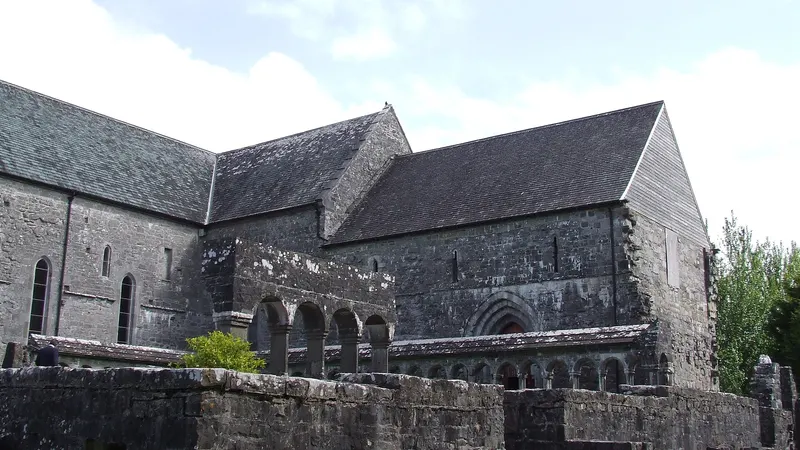The stone nave and transept of Ballintubber Abbey above its graveyard