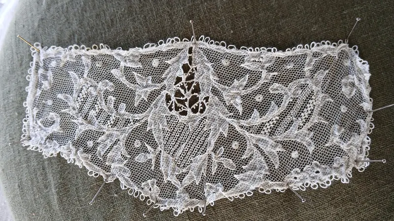 A piece of Carrickmacross lace laid out flat with its needle beside it