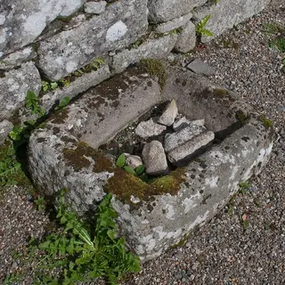 A stone baptismal font set into the wall of the ruined church at Killoughternane