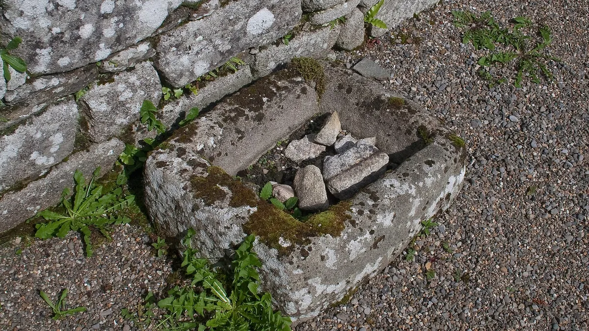 A stone baptismal font set into the wall of the ruined church at Killoughternane