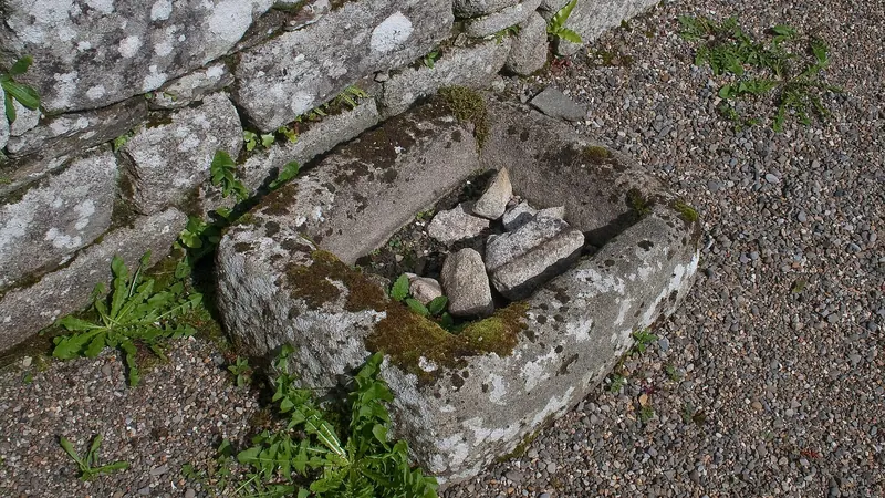A stone baptismal font set into the wall of the ruined church at Killoughternane
