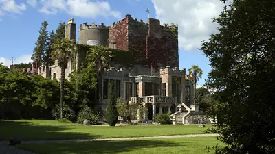 Huntington Castle behind its lawn with palms and mature trees around it