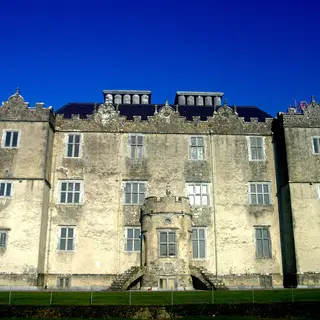 Portumna Castle lit against a dark blue sky with its formal front and corner towers