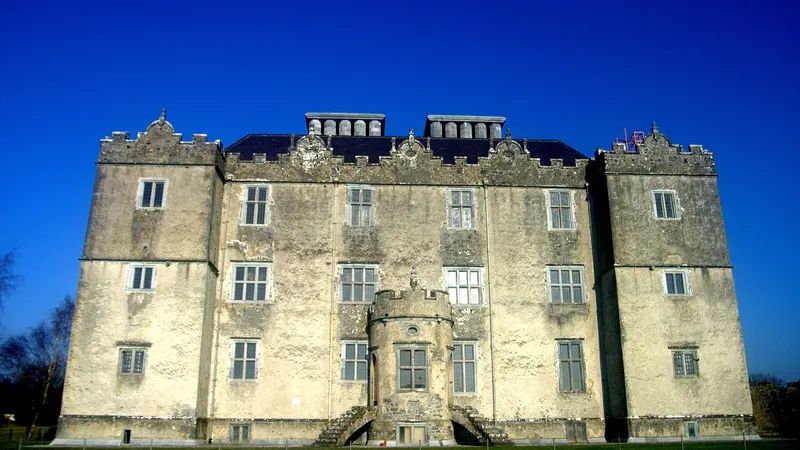 Portumna Castle lit against a dark blue sky with its formal front and corner towers
