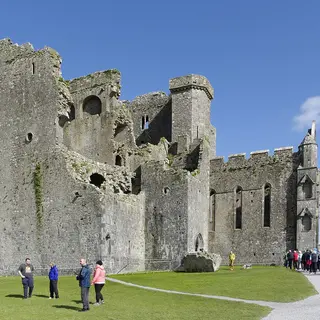 The Rock of Cashel, its cathedral and round tower rising above the grass on a bright day