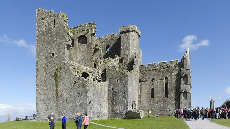 The Rock of Cashel, its cathedral and round tower rising above the grass on a bright day