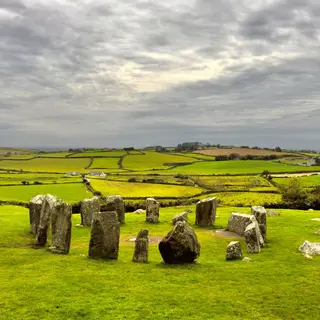 The standing stones of Drombeg stone circle in a green field