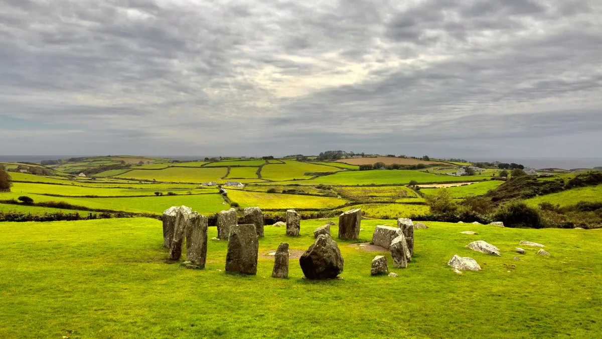The standing stones of Drombeg stone circle in a green field