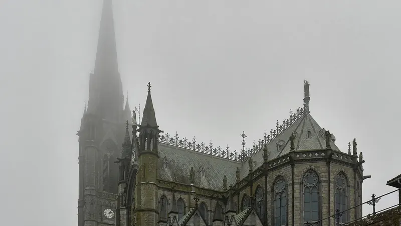 The spire and side of Saint Colman's Cathedral in Cobh in low cloud