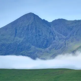 Cloud sitting on the MacGillycuddy's Reeks above green fields