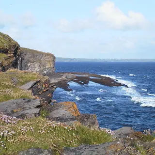 The low cliffs and a rock arch above blue water at Aughris Head