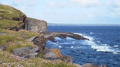 The low cliffs and a rock arch above blue water at Aughris Head