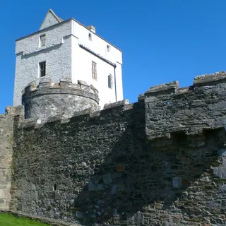 The white tower of Doe Castle behind its stone wall