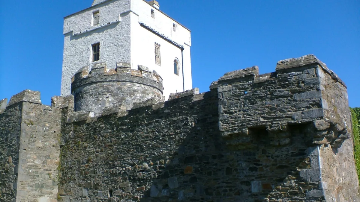 The white tower of Doe Castle behind its stone wall