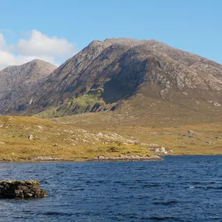 The Connemara mountains behind a still lake under a clear blue sky