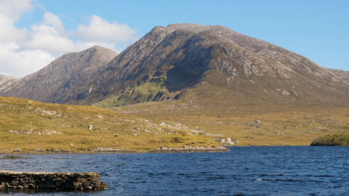 The Connemara mountains behind a still lake under a clear blue sky