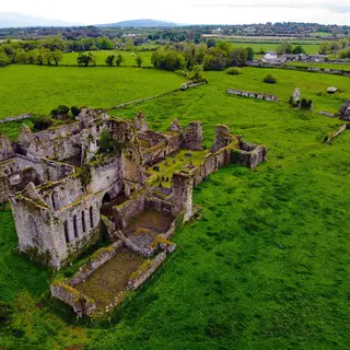 Athassel Abbey from the air, the whole ruin laid out in a green field beside the river