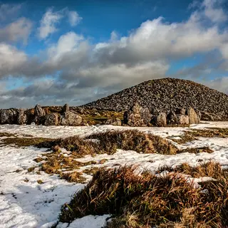 The kerbstones and cairn on the hilltop at Loughcrew with snow in the grass