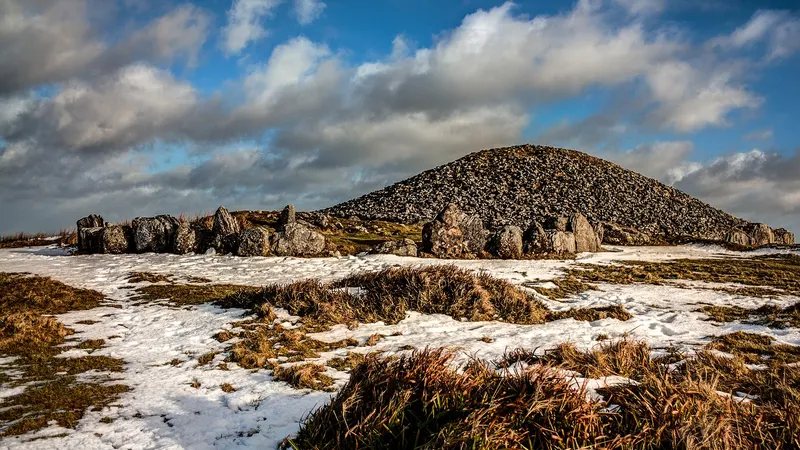 The kerbstones and cairn on the hilltop at Loughcrew with snow in the grass