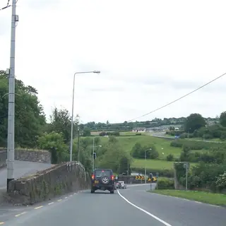 The road through Slane past the stone wall and gate piers of the village