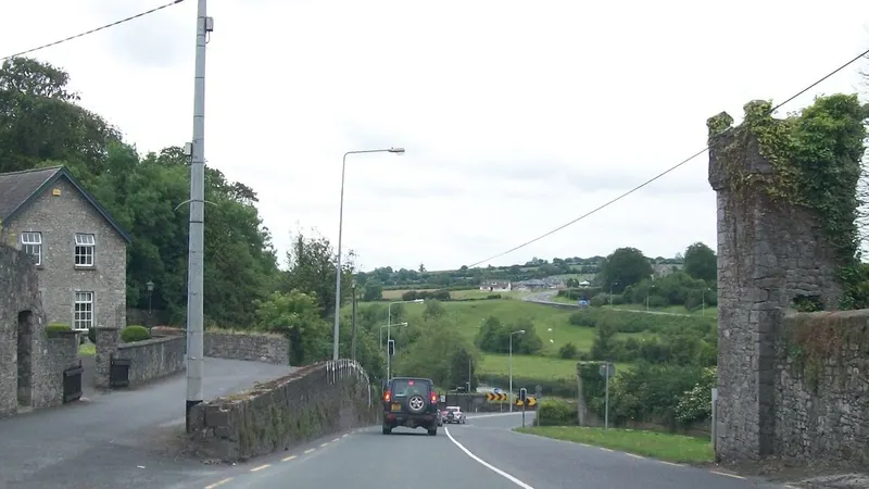 The road through Slane past the stone wall and gate piers of the village