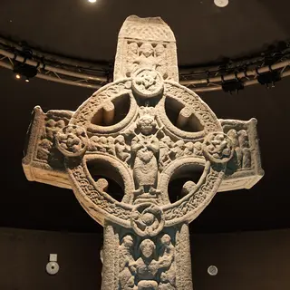 The carved high cross from Clonmacnoise standing under lights in the visitor centre