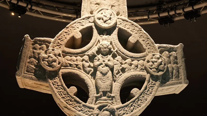 The carved high cross from Clonmacnoise standing under lights in the visitor centre
