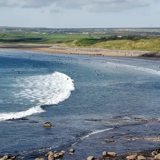 Surf running into the long strand at Lahinch with the dunes behind