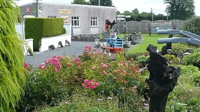 Flower beds and old machinery in the yard outside Derryglad Folk Heritage Museum