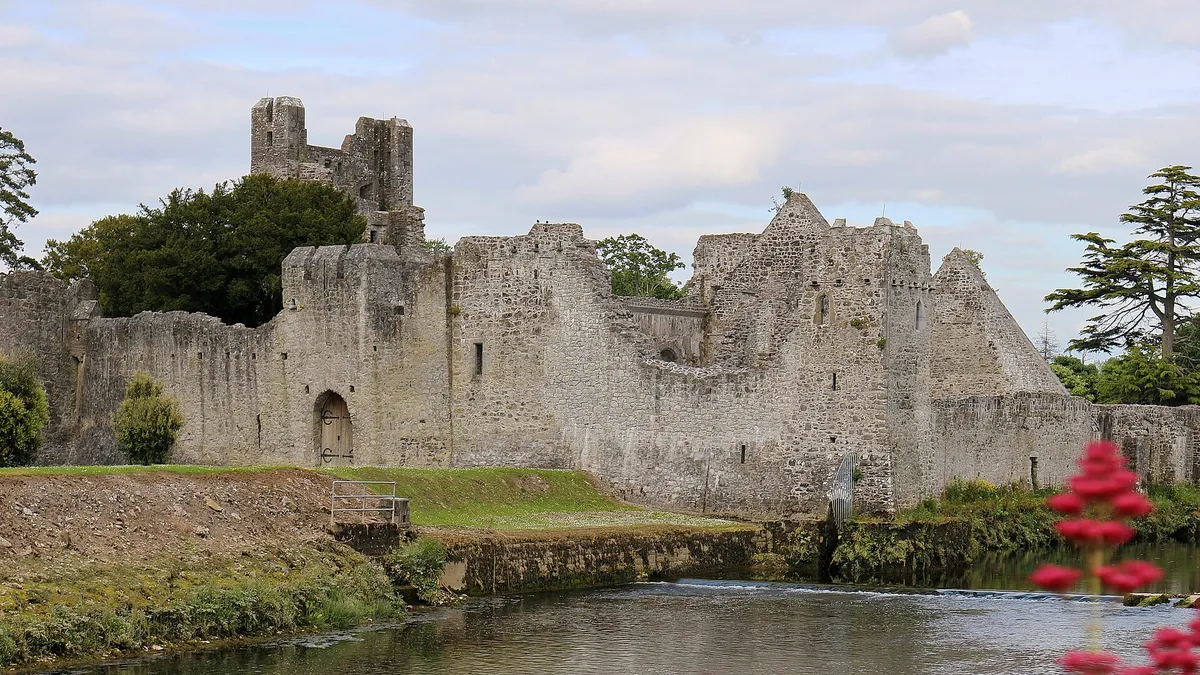 Desmond Castle at Adare with its walls and moat coming down to the river