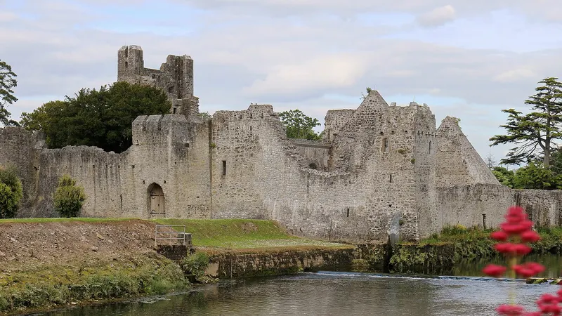 Desmond Castle at Adare with its walls and moat coming down to the river