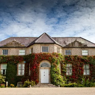 The ivy covered front of the house at Altamont with red creeper across the stonework