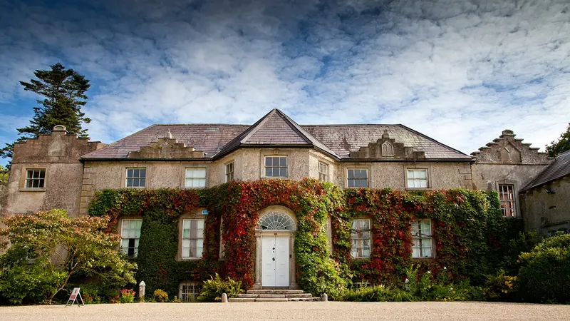 The ivy covered front of the house at Altamont with red creeper across the stonework
